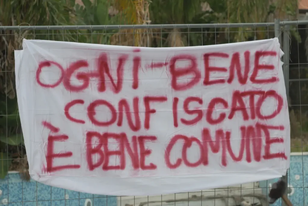 telo con scritta in rosso " ogni bene confiscato è bene comune"