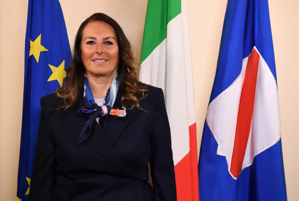 Ritratto istituzionale dell’assessora regionale Fiorella Zabatta davanti alle bandiere europea, italiana e regionale.