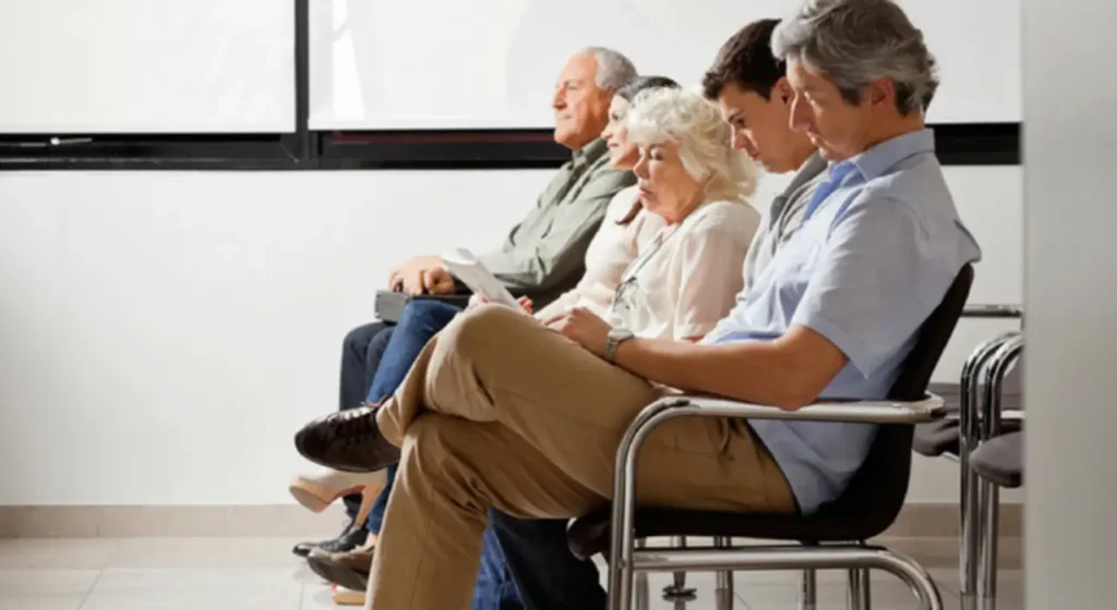 Pazienti seduti in una sala d’attesa sanitaria in attesa di visite ed esami medici.